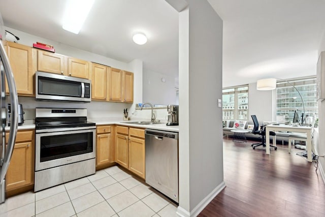 kitchen with light brown cabinets, sink, light tile patterned floors, and stainless steel appliances