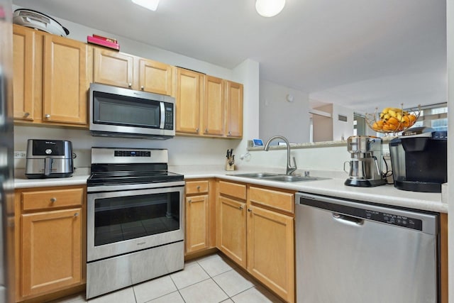 kitchen with sink, light tile patterned floors, light brown cabinets, and appliances with stainless steel finishes