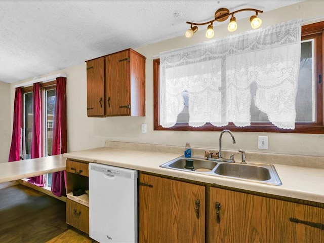 kitchen with light wood-type flooring, a textured ceiling, white dishwasher, and sink