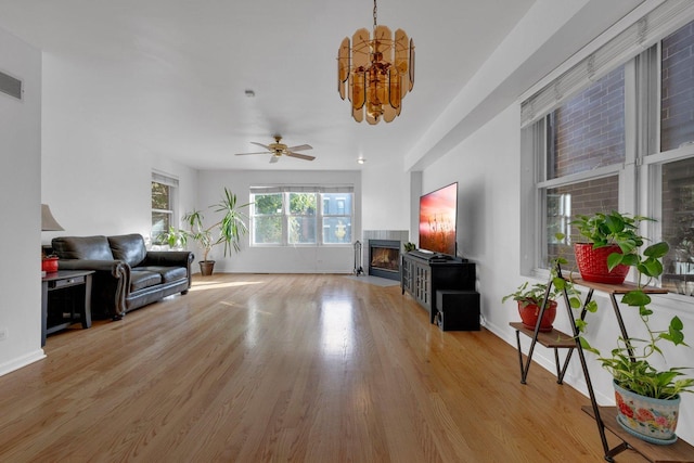 living room with ceiling fan with notable chandelier and light wood-type flooring