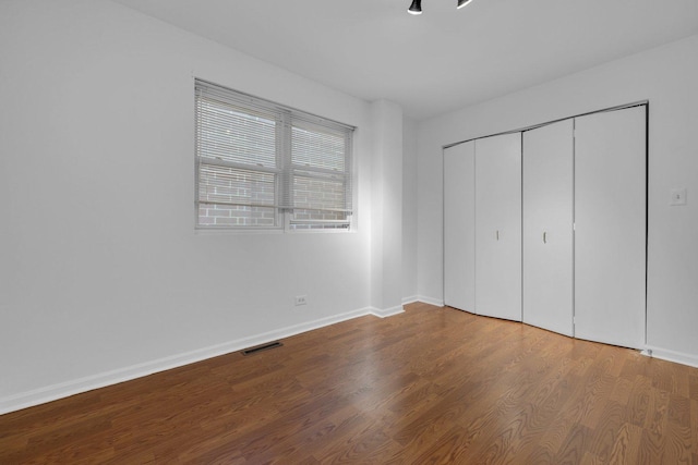 unfurnished bedroom featuring a closet and hardwood / wood-style floors