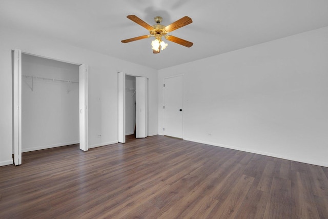 unfurnished bedroom with multiple closets, ceiling fan, and dark hardwood / wood-style floors