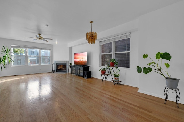 unfurnished living room featuring ceiling fan, light hardwood / wood-style floors, and a tiled fireplace