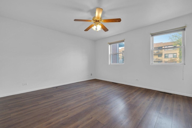 spare room with dark hardwood / wood-style flooring, ceiling fan, and plenty of natural light