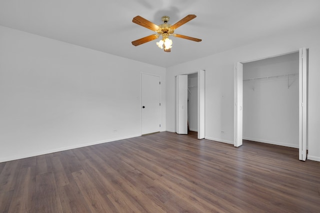 unfurnished bedroom with ceiling fan, dark hardwood / wood-style floors, and two closets