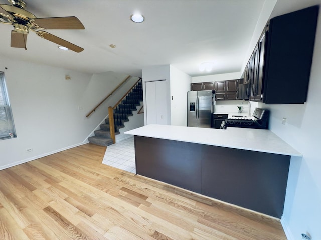 kitchen with ceiling fan, stainless steel appliances, kitchen peninsula, dark brown cabinets, and light wood-type flooring