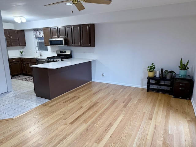 kitchen featuring kitchen peninsula, dark brown cabinetry, stainless steel appliances, sink, and light hardwood / wood-style floors