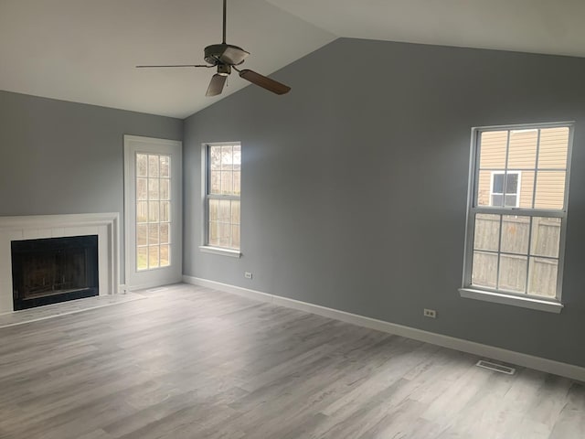 unfurnished living room featuring light hardwood / wood-style floors, ceiling fan, lofted ceiling, and a tiled fireplace