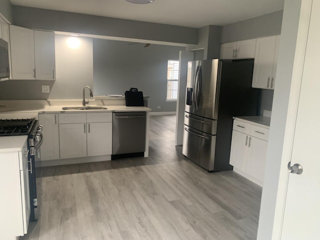 kitchen with white cabinetry, sink, stainless steel appliances, and light hardwood / wood-style floors