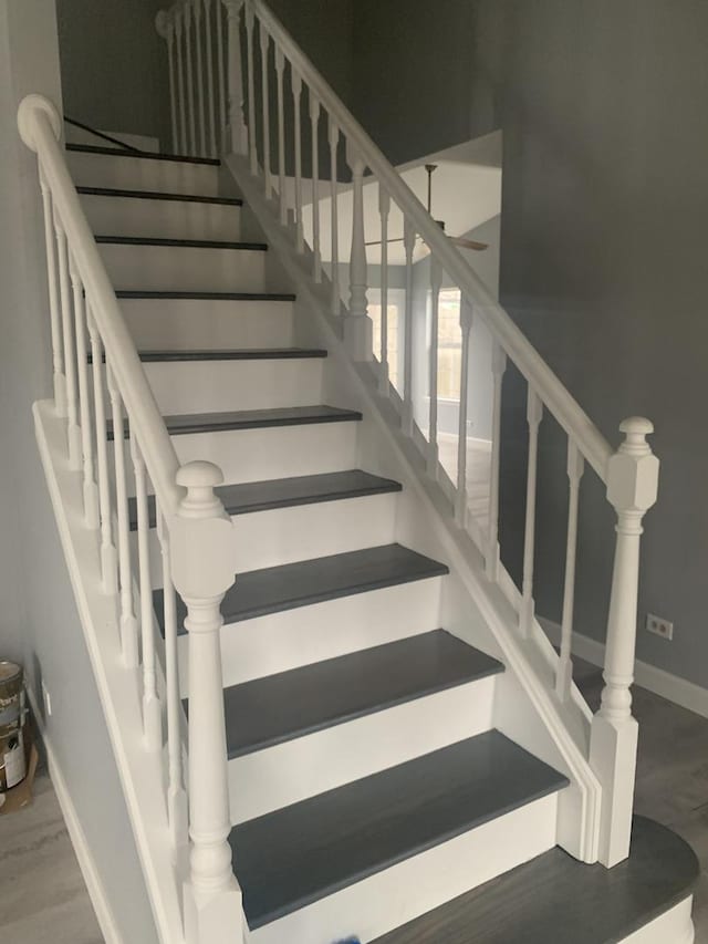 staircase with ceiling fan and wood-type flooring