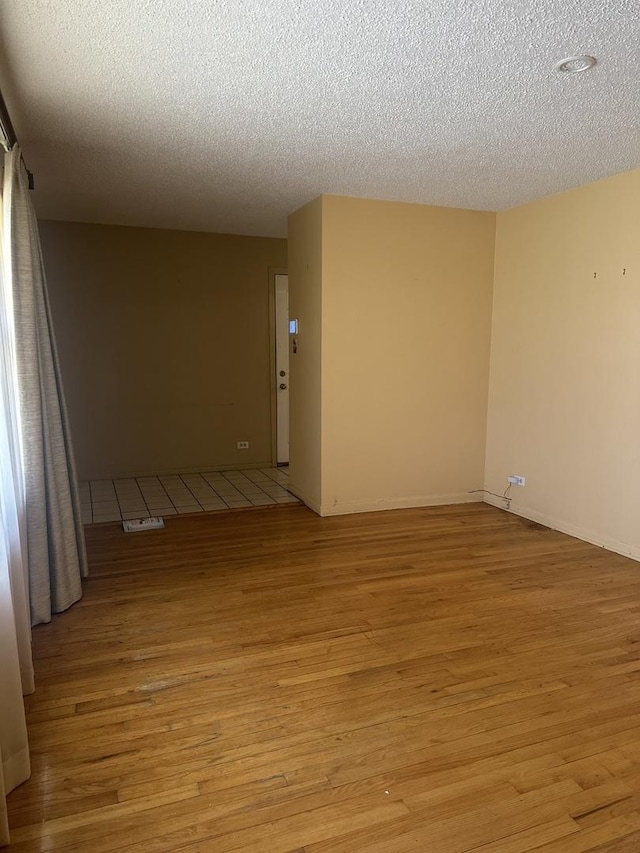 spare room featuring a textured ceiling and light wood-type flooring