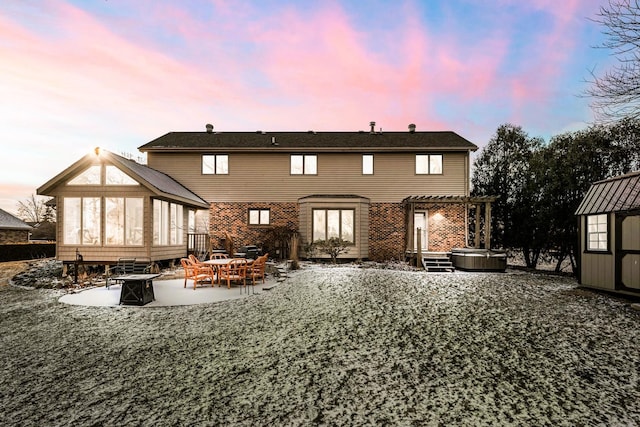 back house at dusk featuring a shed, a pergola, a patio, an outdoor fire pit, and a hot tub