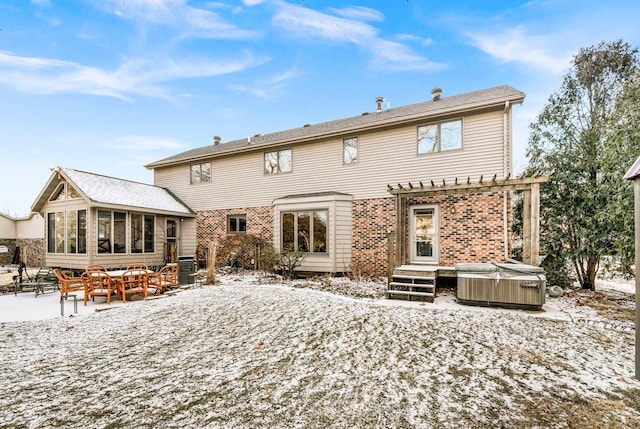 snow covered back of property with a pergola, a sunroom, a hot tub, and central air condition unit