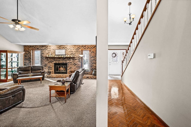 living room with brick wall, ceiling fan with notable chandelier, parquet floors, a high ceiling, and a brick fireplace