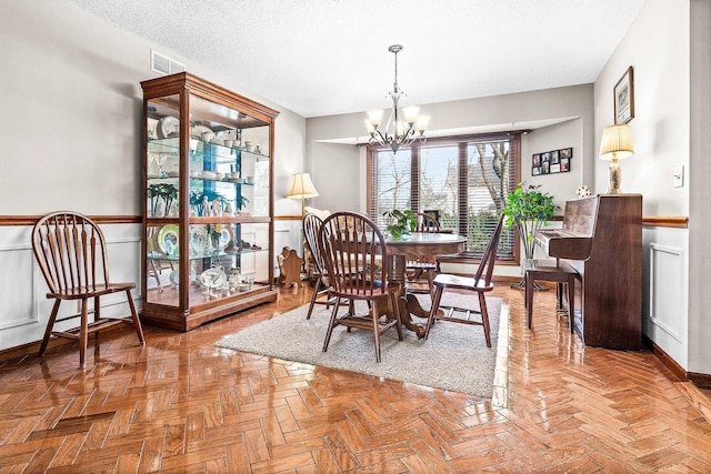 dining space with an inviting chandelier, light parquet flooring, and a textured ceiling