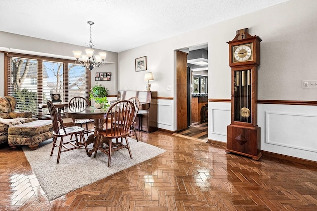 dining area featuring dark parquet floors, a notable chandelier, and a textured ceiling