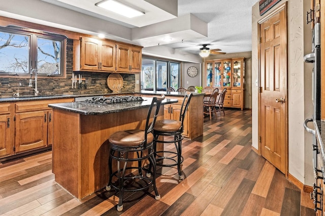 kitchen featuring a breakfast bar, sink, a center island, stainless steel gas stovetop, and hardwood / wood-style floors