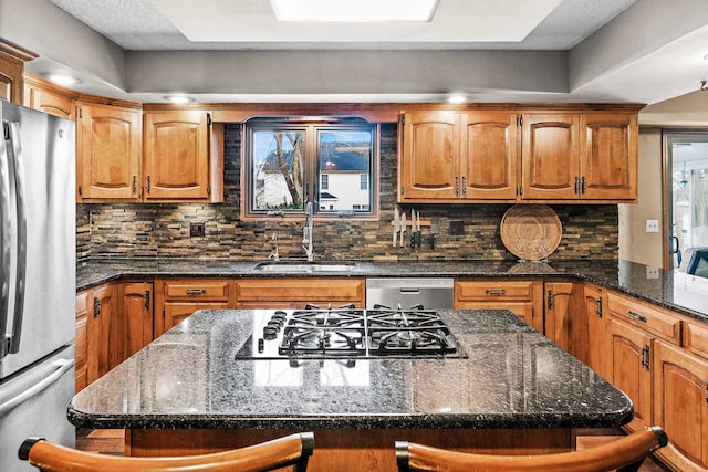 kitchen with stainless steel appliances, sink, a breakfast bar area, and dark stone counters