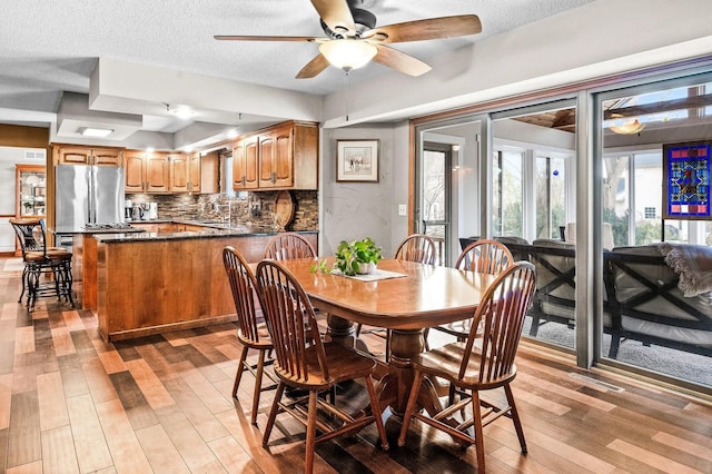 dining space with sink, light hardwood / wood-style floors, a textured ceiling, and ceiling fan