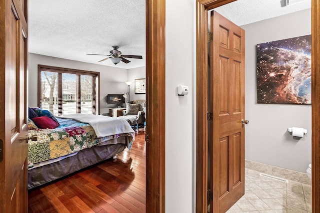 bedroom featuring ceiling fan, light hardwood / wood-style floors, and a textured ceiling