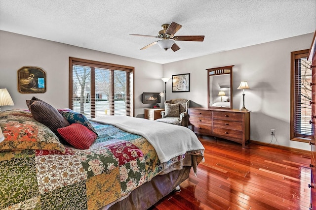 bedroom featuring ceiling fan, access to exterior, hardwood / wood-style floors, and a textured ceiling