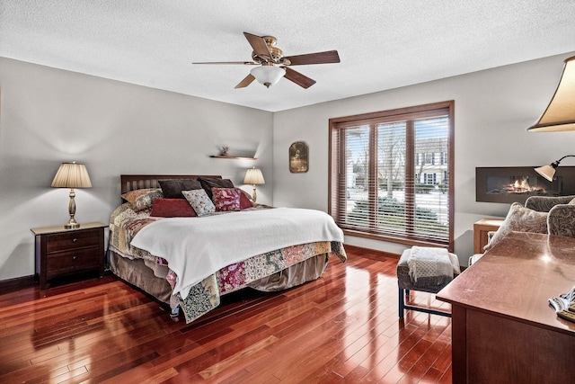 bedroom with ceiling fan, dark wood-type flooring, and a textured ceiling