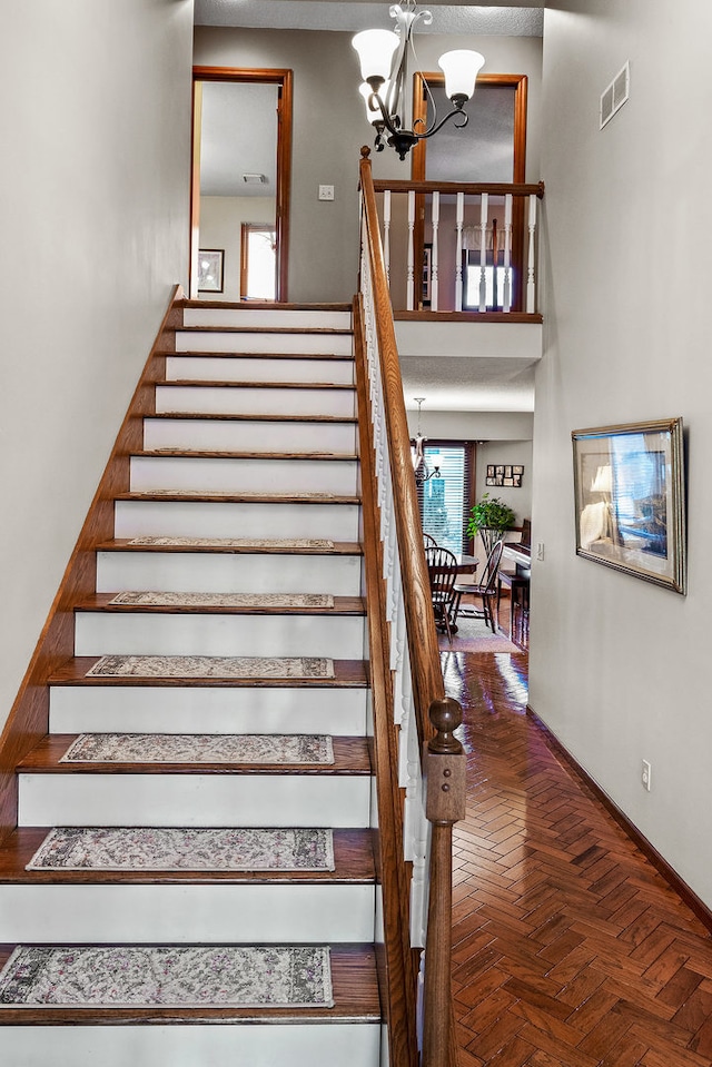 staircase with an inviting chandelier, parquet floors, and a high ceiling