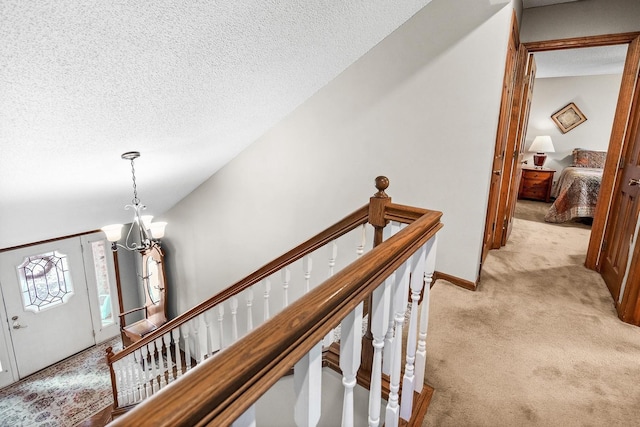 interior space featuring light colored carpet, a textured ceiling, and a notable chandelier