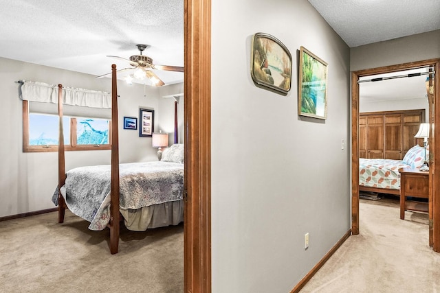 bedroom with ceiling fan, light colored carpet, and a textured ceiling