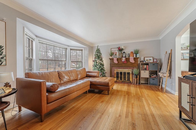 living room featuring crown molding, light hardwood / wood-style floors, and a brick fireplace