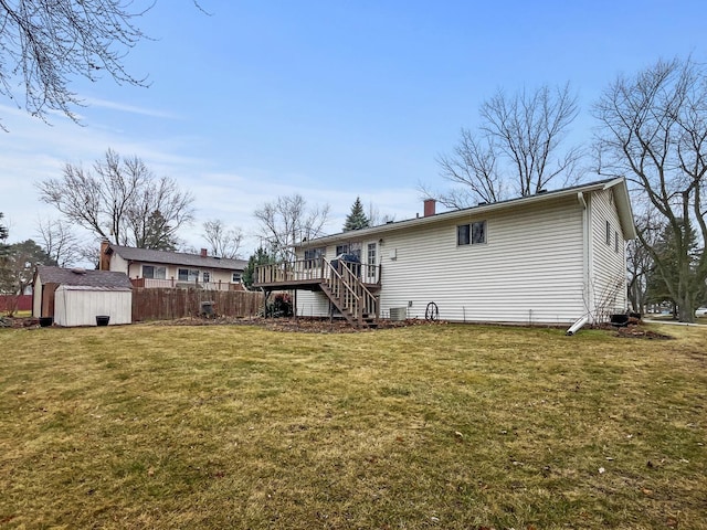 rear view of house featuring a lawn, a storage unit, and a wooden deck