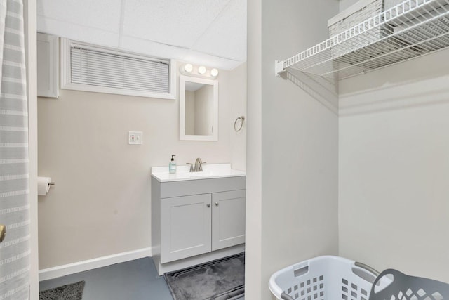 bathroom with vanity, concrete floors, and a drop ceiling