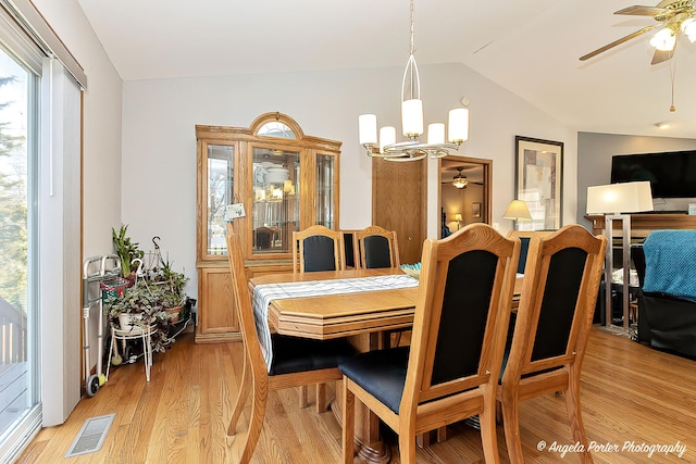 dining area featuring ceiling fan with notable chandelier, light hardwood / wood-style floors, and lofted ceiling