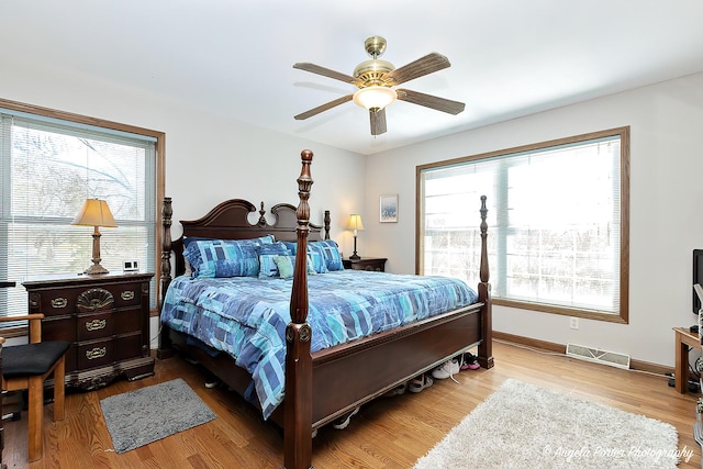 bedroom with multiple windows, ceiling fan, and hardwood / wood-style flooring