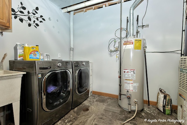 clothes washing area with washing machine and clothes dryer, cabinets, and gas water heater