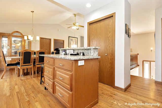 kitchen featuring a center island, pendant lighting, vaulted ceiling, and light wood-type flooring