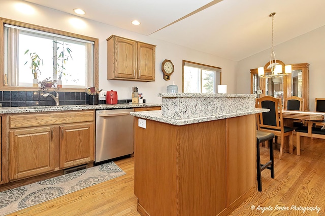 kitchen featuring tasteful backsplash, stainless steel dishwasher, pendant lighting, light hardwood / wood-style floors, and a kitchen island