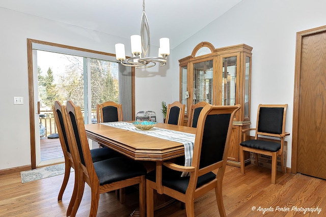 dining space with lofted ceiling, light wood-type flooring, and a chandelier