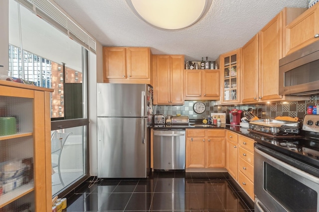 kitchen with light brown cabinets, a textured ceiling, tasteful backsplash, and appliances with stainless steel finishes