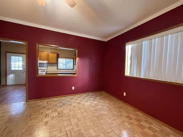 empty room with ceiling fan, a textured ceiling, and light parquet floors