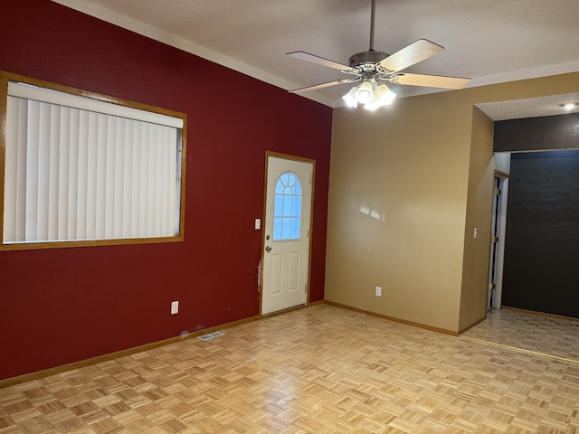 interior space with ceiling fan, a textured ceiling, and light parquet flooring