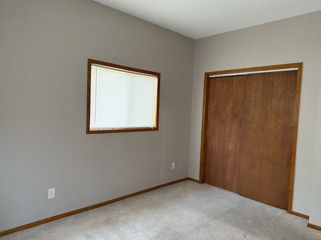 unfurnished bedroom featuring light carpet and a closet