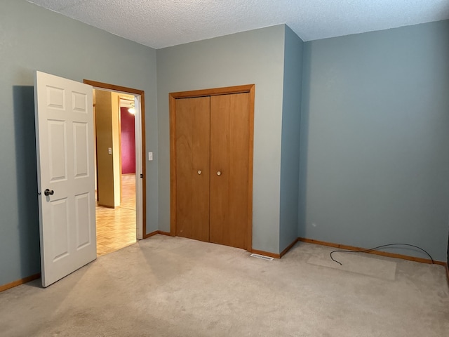 unfurnished bedroom with light colored carpet, a textured ceiling, and a closet