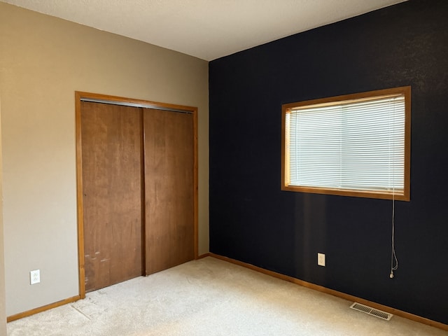 unfurnished bedroom featuring light colored carpet and a closet