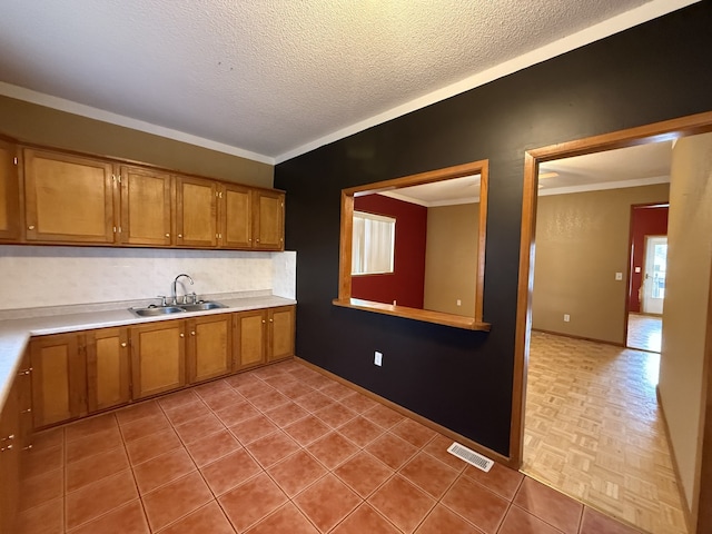 kitchen with backsplash, crown molding, sink, and a textured ceiling