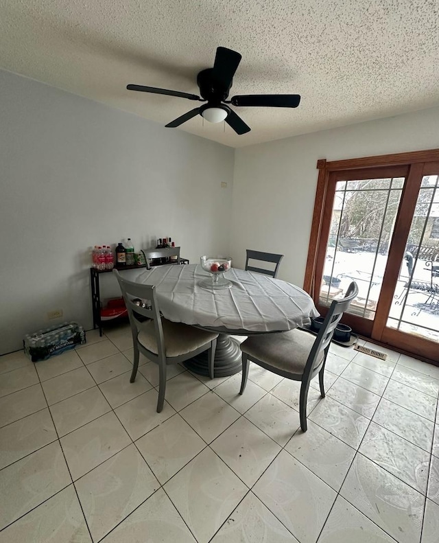 dining area with a textured ceiling, ceiling fan, and light tile patterned flooring