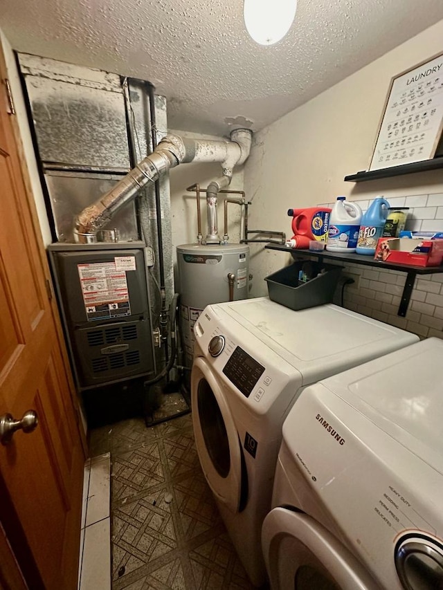 laundry area featuring washing machine and clothes dryer, water heater, and a textured ceiling