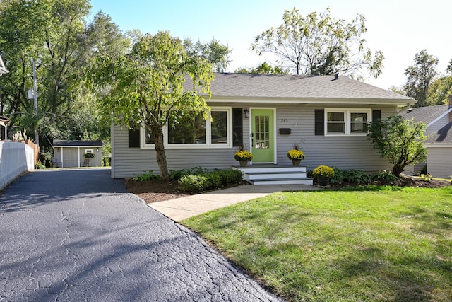 single story home featuring a front lawn and a shed