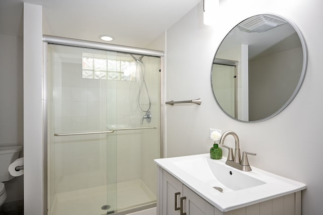 bathroom featuring vanity, an enclosed shower, and toilet