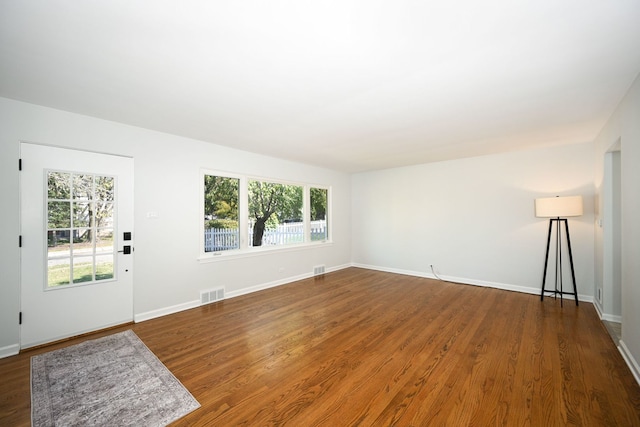 unfurnished living room featuring plenty of natural light and dark wood-type flooring